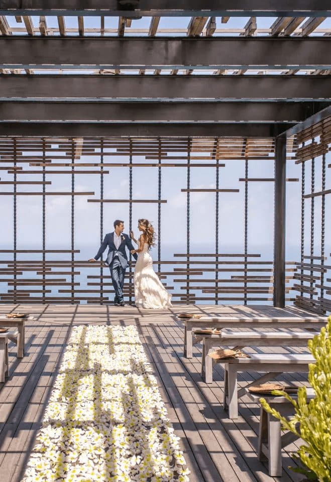 Alila Uluwatu — a couple beneath the timber pavilion above the ocean · Uluwatu, Indonesia