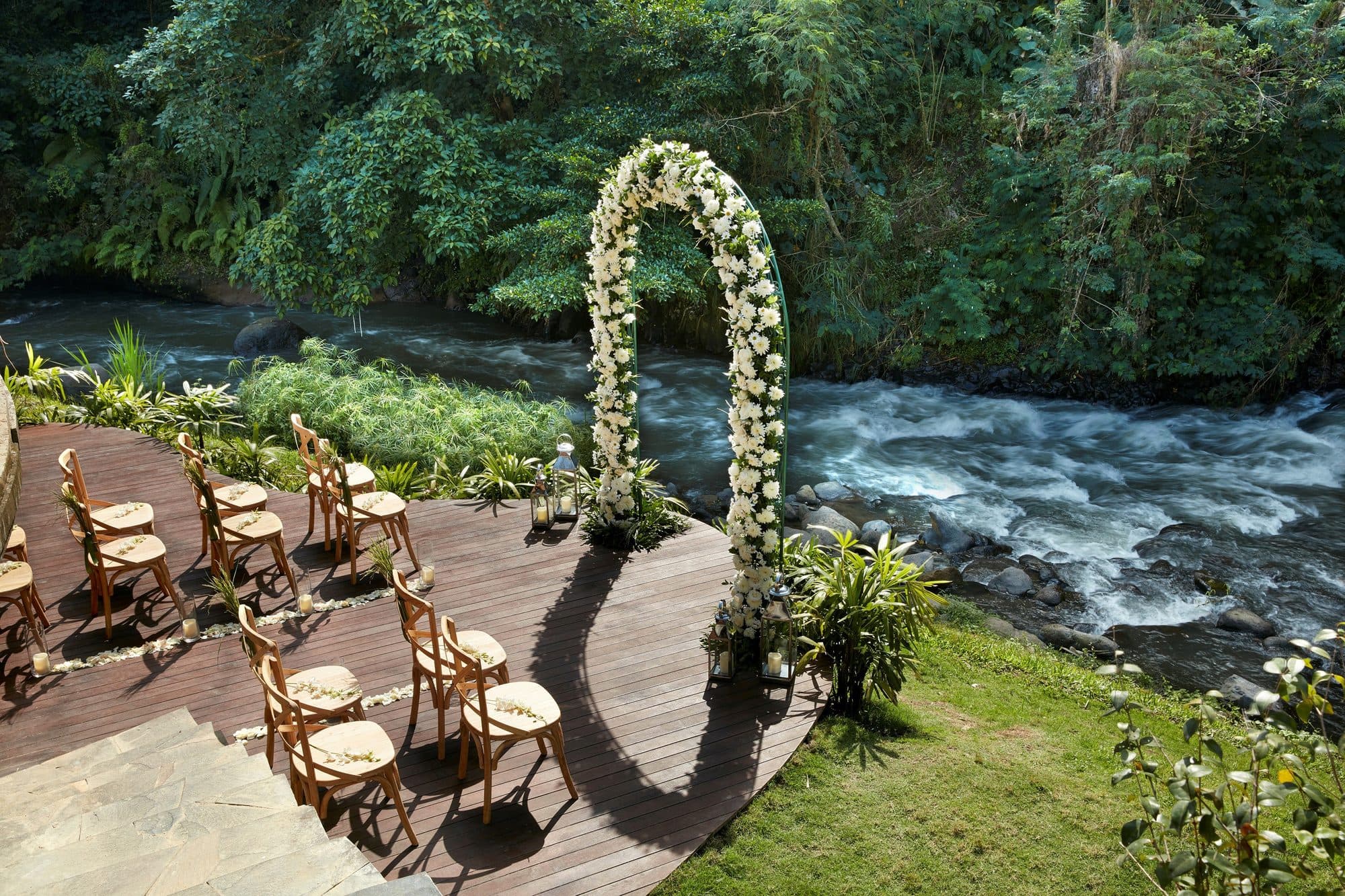 Mandapa, a Ritz-Carlton Reserve — a ceremony set on the river deck beneath a floral arch · Ubud, Indonesia