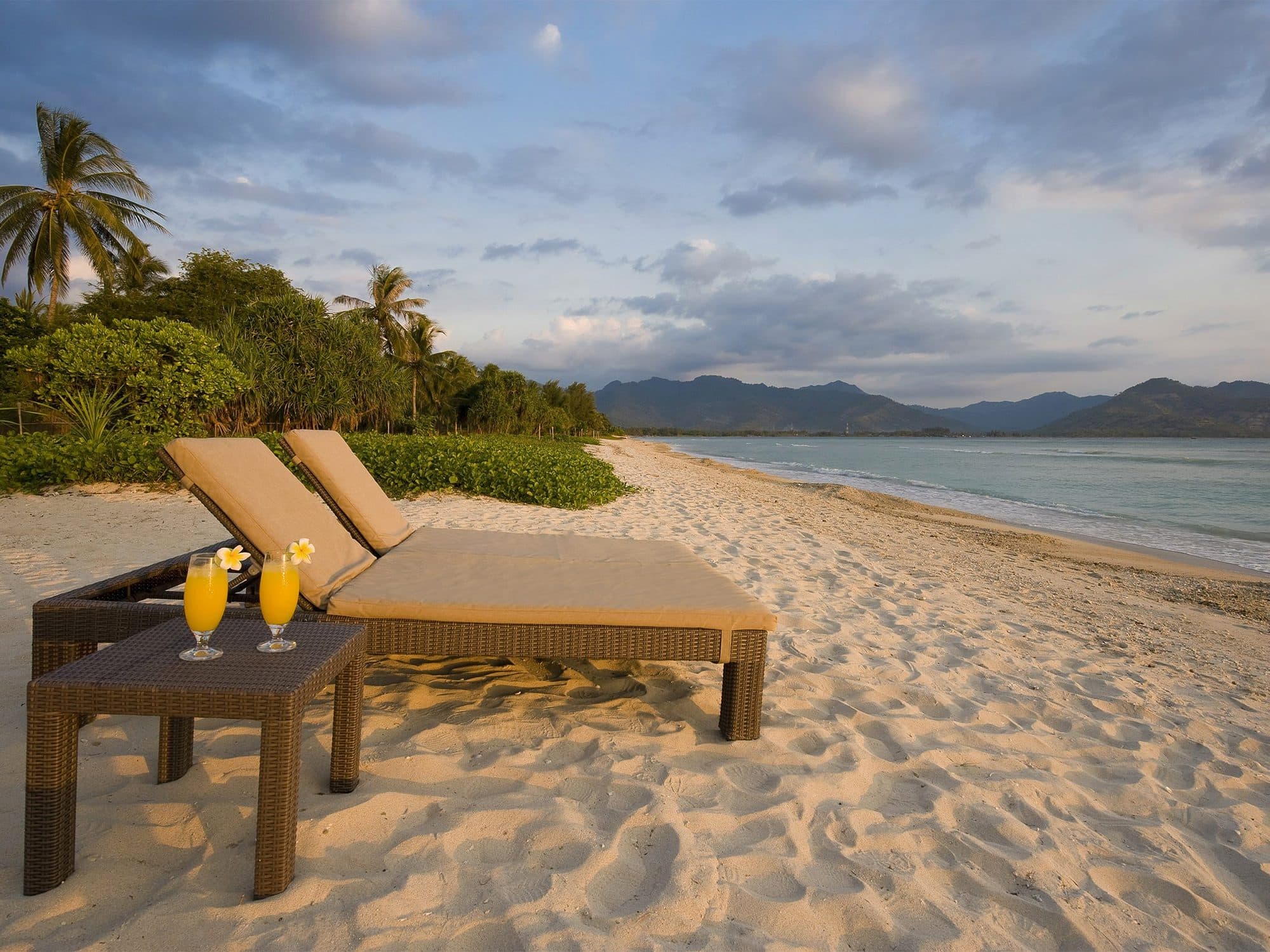 Sepoi Sepoi — two loungers on the beach, mountains across the water · Lombok, Indonesia