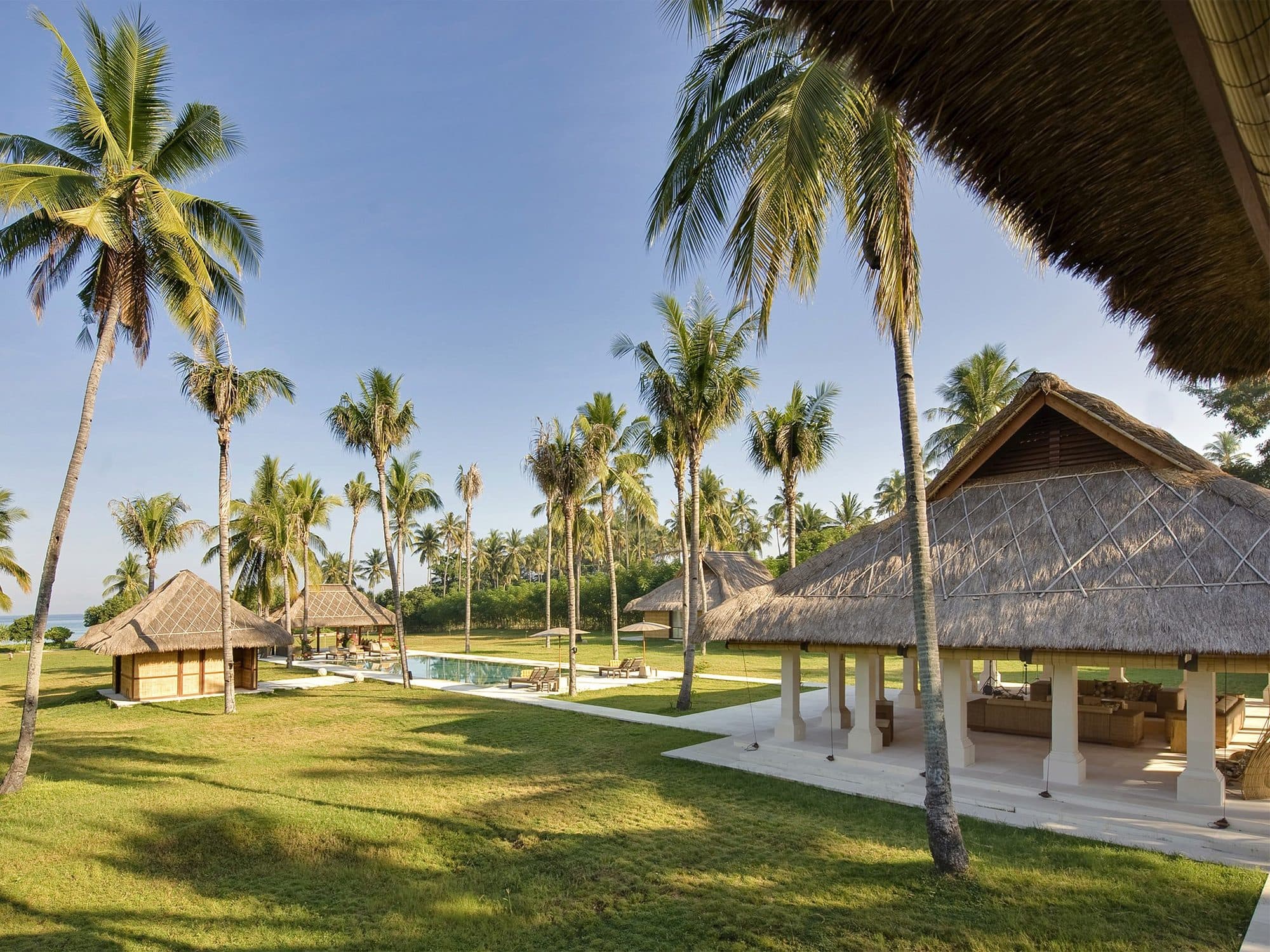 Sepoi Sepoi — thatched pavilions on the lawn beneath palms · Lombok, Indonesia