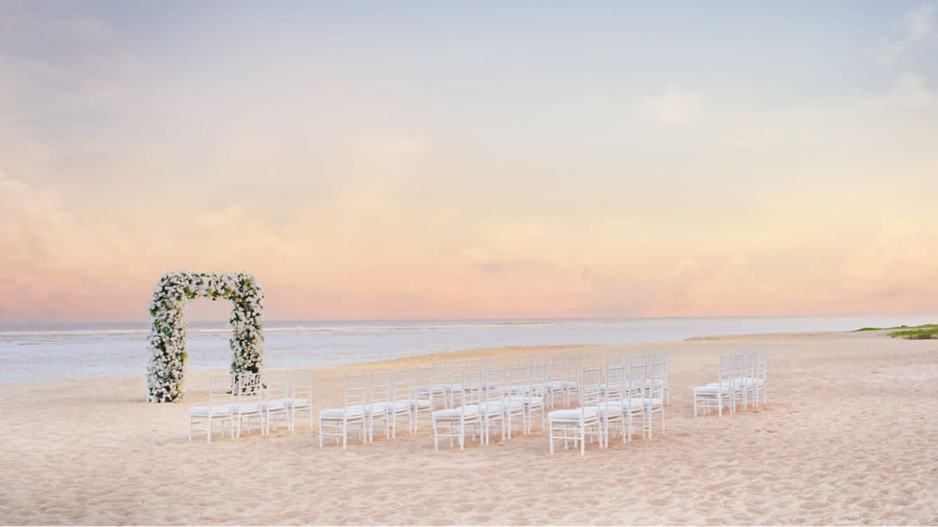 The Ritz Carlton Bali — a beach ceremony set with a floral arch · Nusa Dua, Indonesia