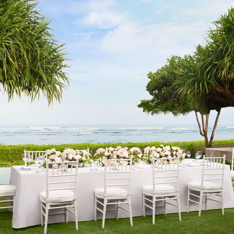 The Ritz Carlton Bali — a long table set on the lawn above the beach · Nusa Dua, Indonesia