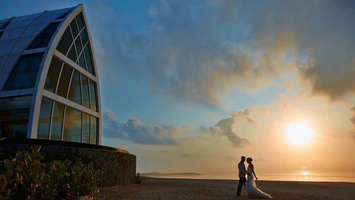 The Ritz Carlton Bali — a couple on the beach at sunset beside the chapel · Nusa Dua, Indonesia