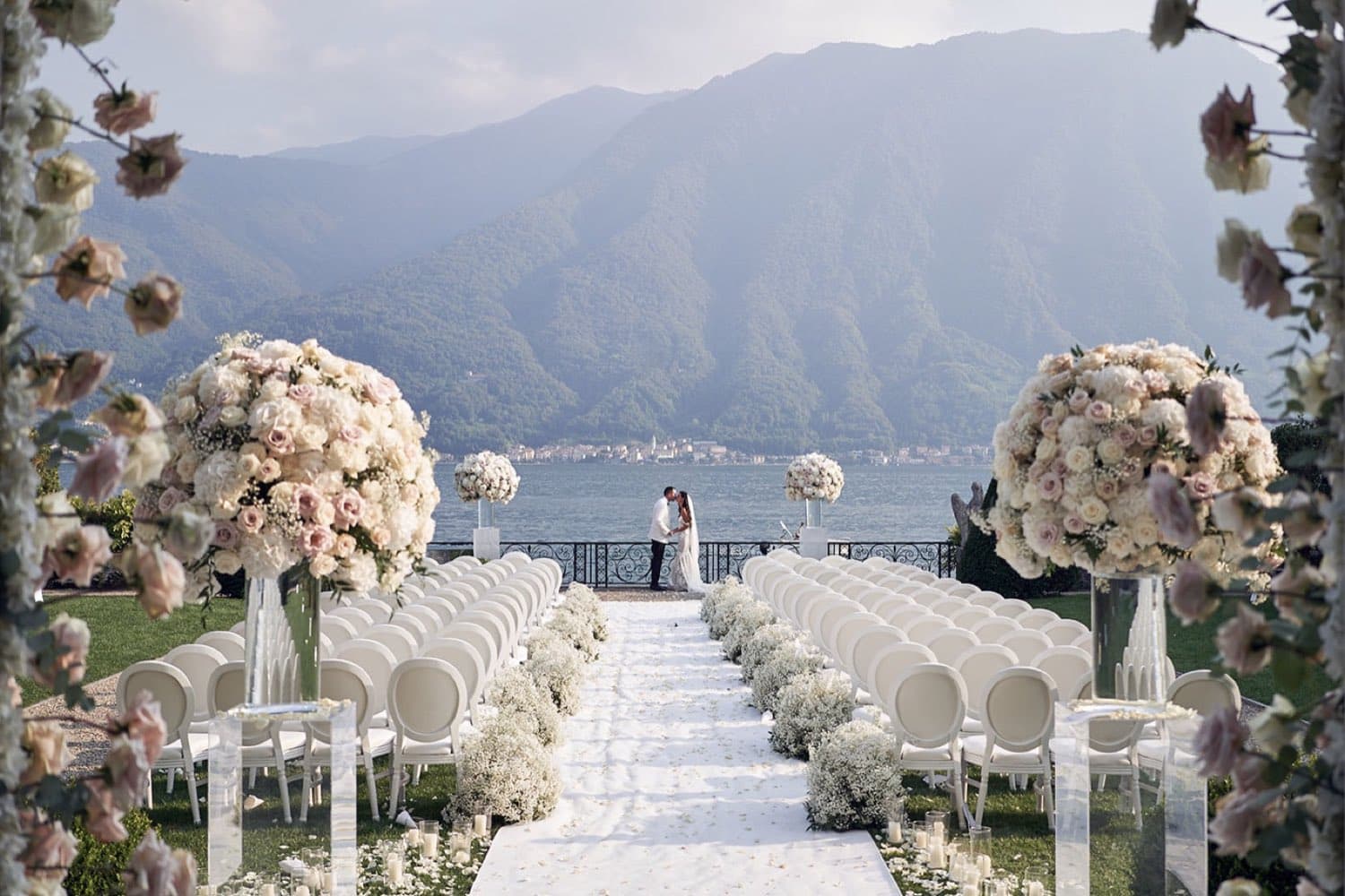Villa Balbiano — wedding ceremony on the lakeside terrace, white chairs and floral columns facing the mountains · Lake Como, Italy