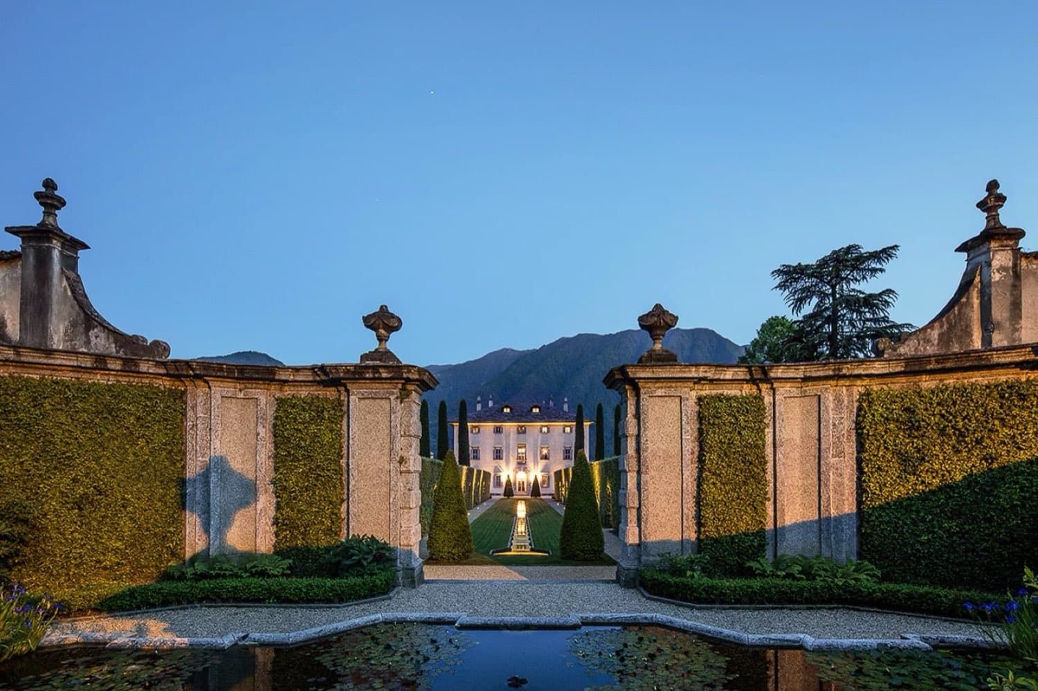Villa Balbiano — the villa at dusk seen through the stone garden gates and reflecting pool · Lake Como, Italy
