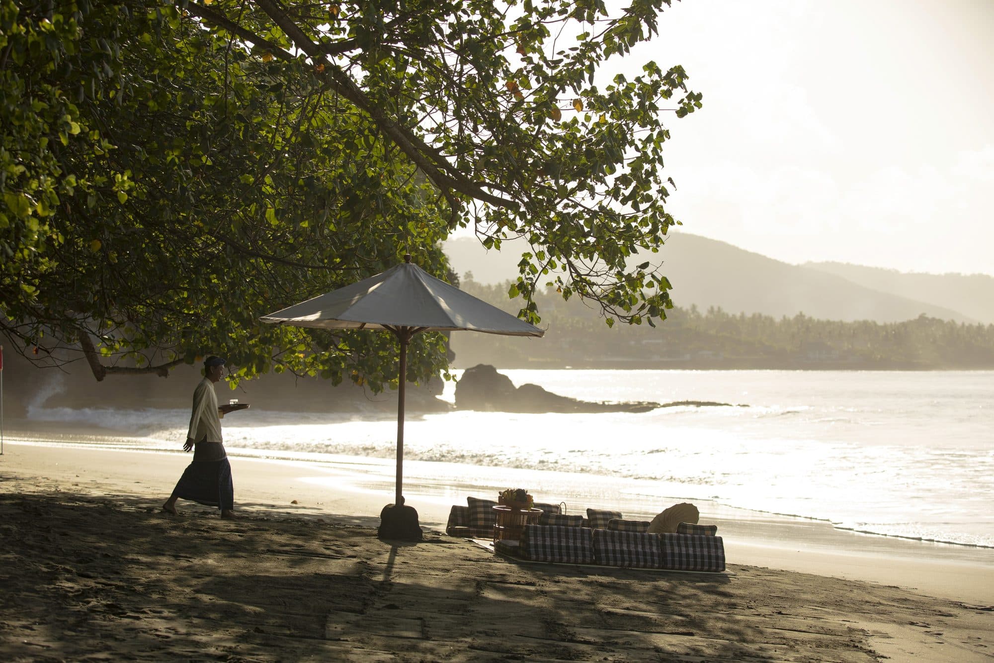 Amankila — a picnic set on the beach beneath the trees · Manggis, Indonesia