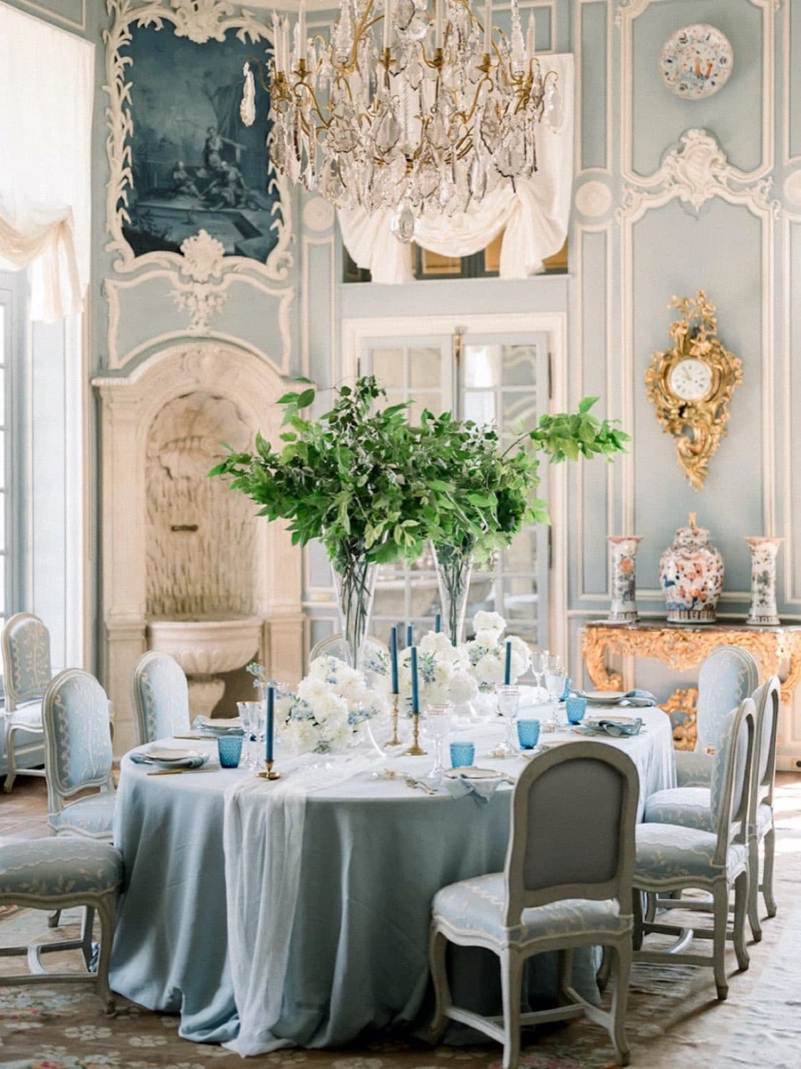 Chateau de Villette — a dinner table set in a pale-blue panelled salon under a chandelier · Paris, France