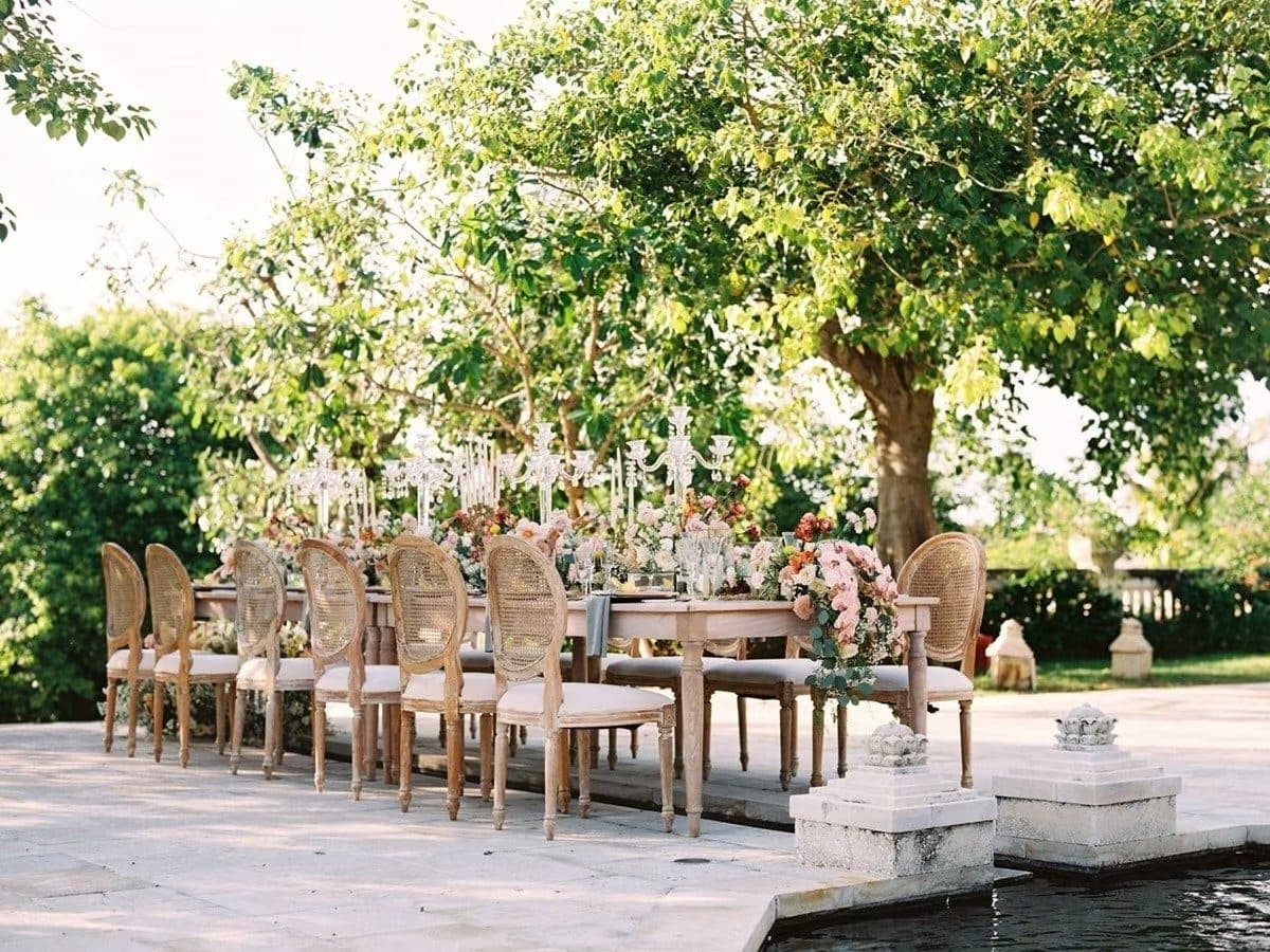 Jumeirah Bali — a long table dressed with flowers beneath the trees · Uluwatu, Indonesia