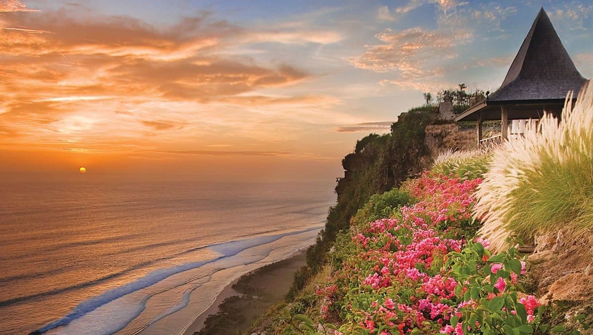 Khayangan Estate — the clifftop pavilion and gardens at sunset above the beach · Uluwatu, Indonesia