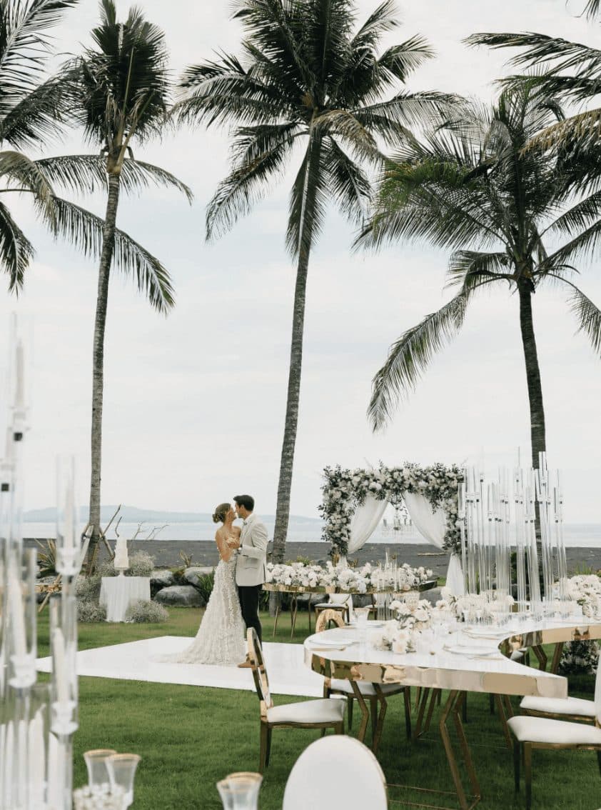 Saba Estate — a couple at a reception set on the lawn among palms · Saba, Indonesia