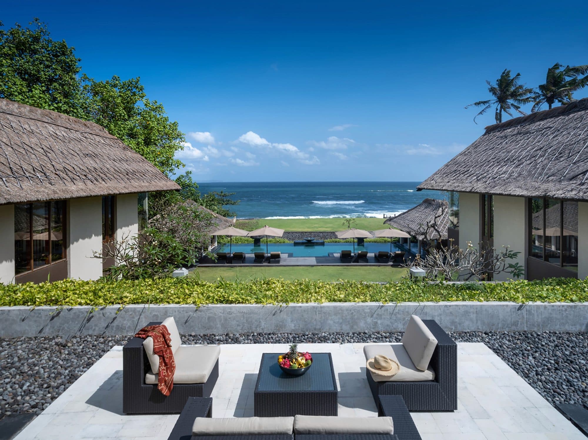 Seseh Beach Villas — a sofa terrace between thatched pavilions, the sea beyond · Seseh, Indonesia