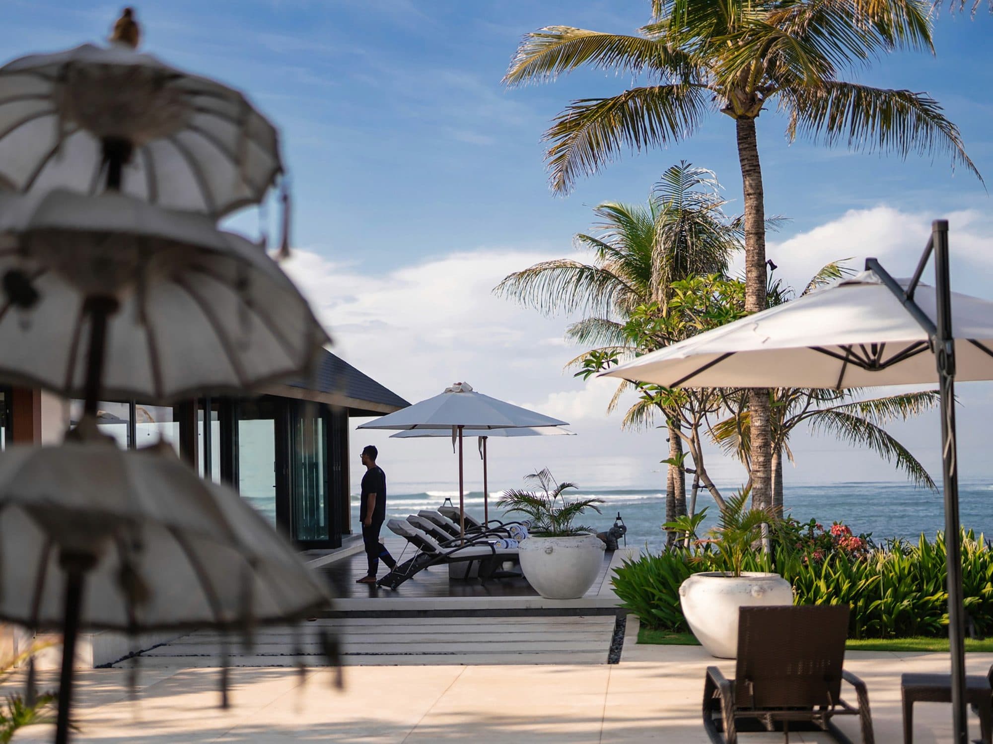 Tirtha Bayu Estate — the pool terrace with parasols by the sea · Seseh, Indonesia