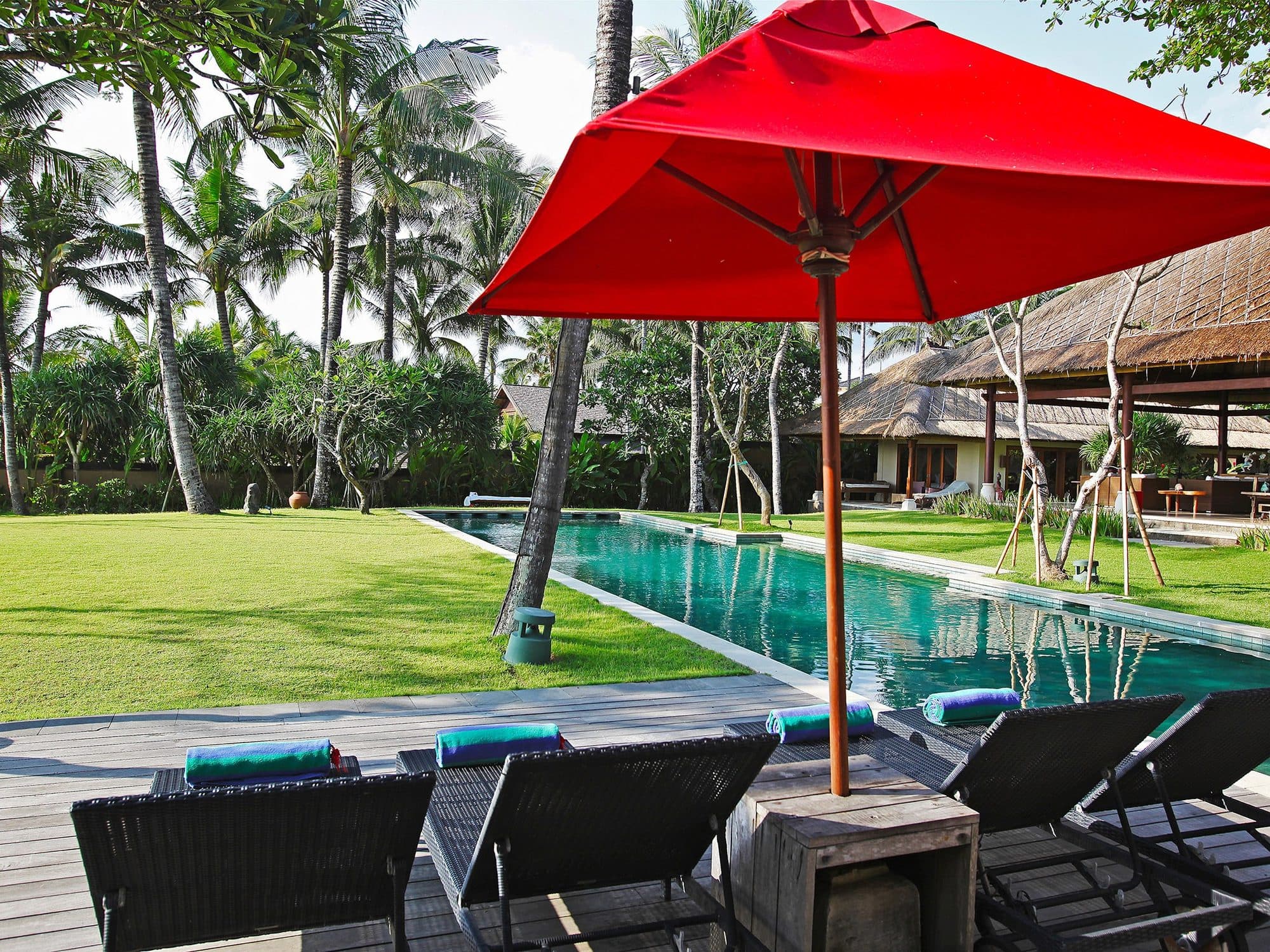 Villa Maridadi — loungers and a red parasol beside the long pool · Cemagi, Indonesia