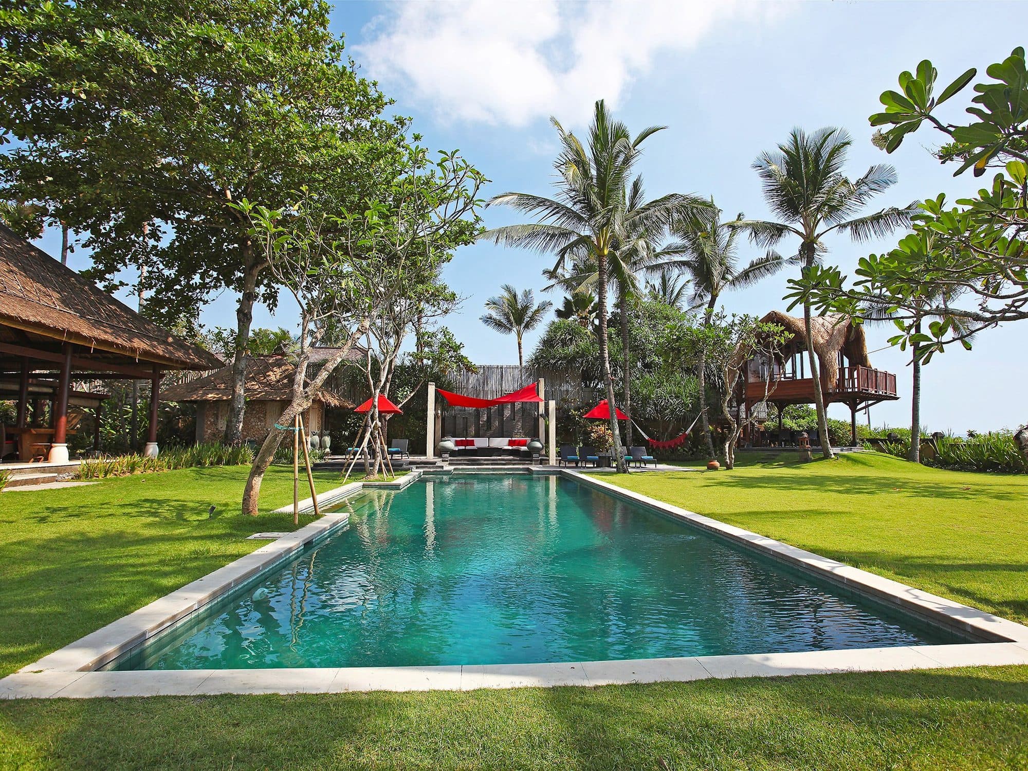 Villa Maridadi — the long pool among palms and thatched pavilions · Cemagi, Indonesia