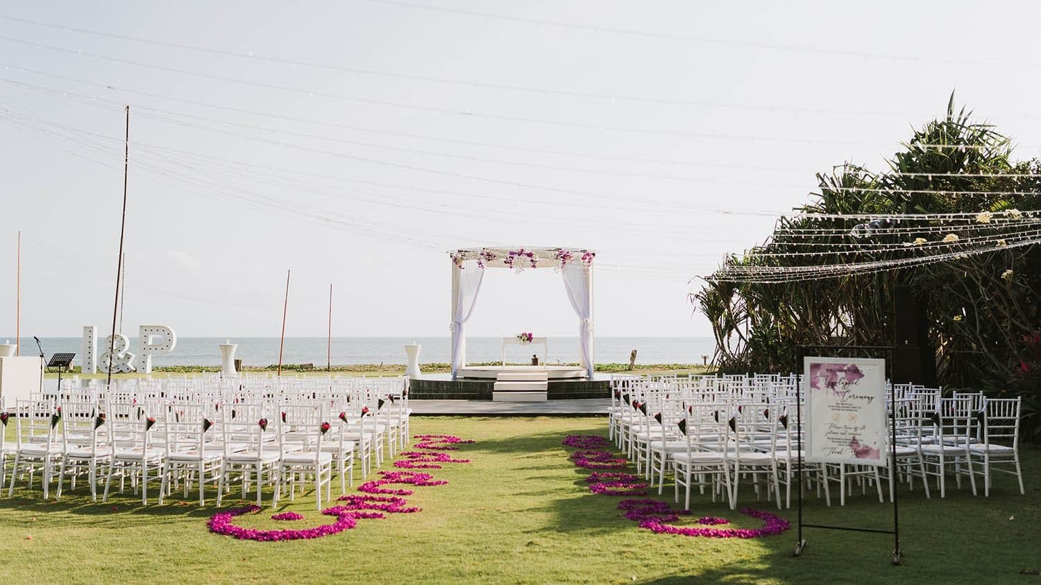 Villa Phalosa — a ceremony aisle lined with pink petals on the lawn · Seseh, Indonesia