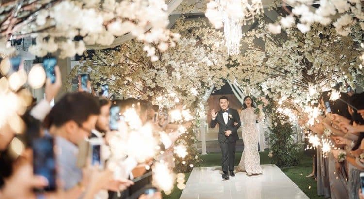 Villa Phalosa — a couple walking through a blossom-covered aisle · Seseh, Indonesia