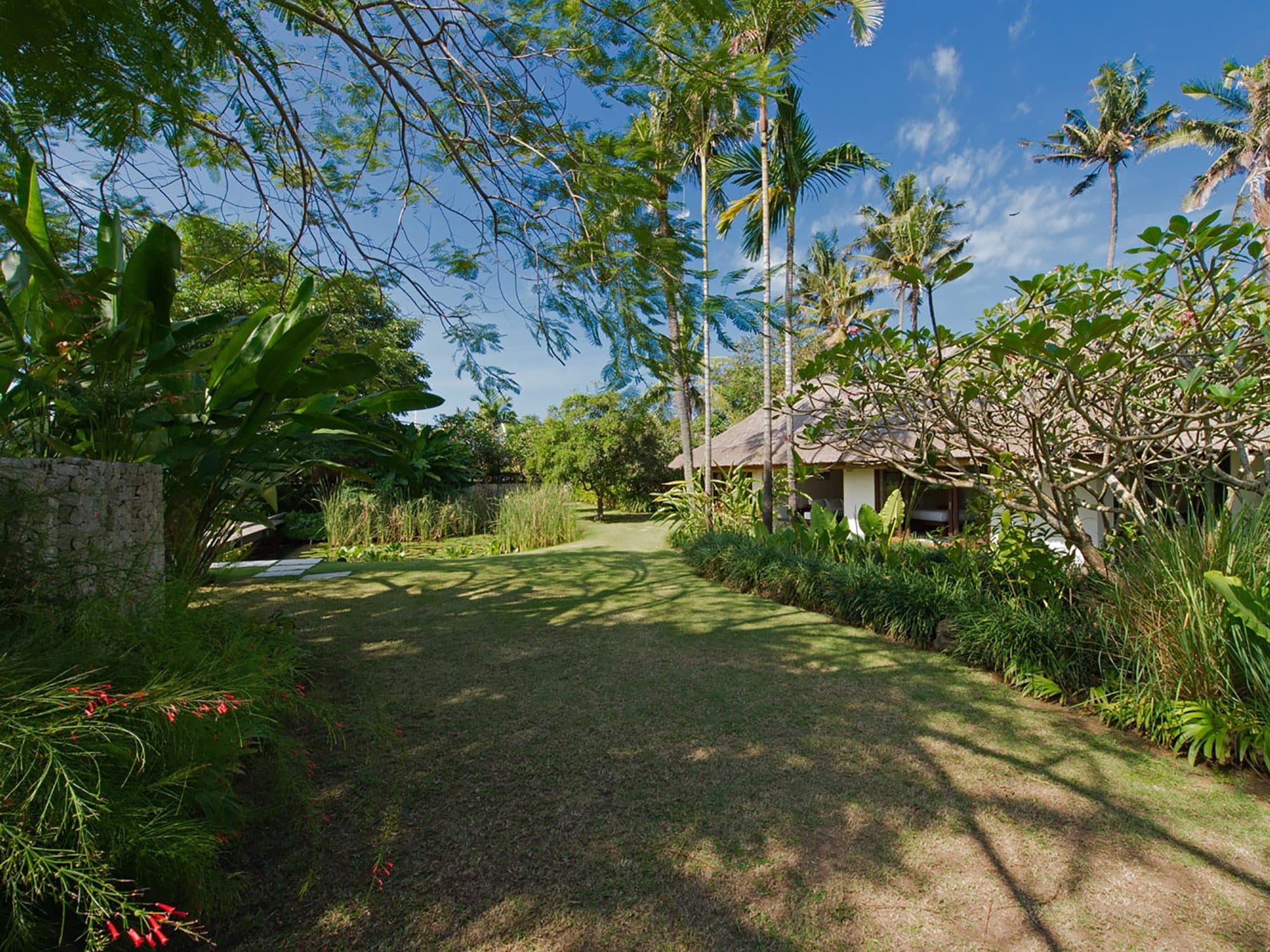 Villa Samadhana — the garden lawn and thatched cottage · Ketewel, Indonesia